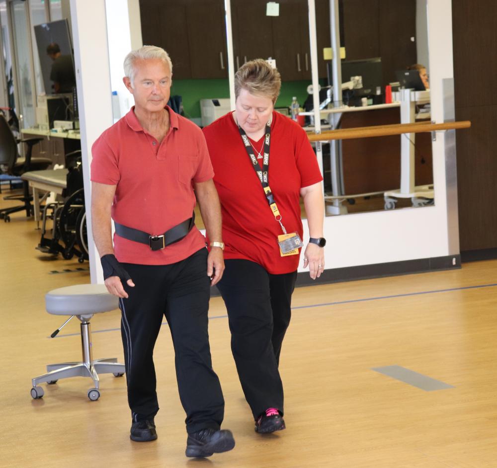 VCU Health N.O.W Center physical therapist Mary Beth O’Reilly walks with Gary Rogliano during a therapy session in August. Photo: Paul Brockwell